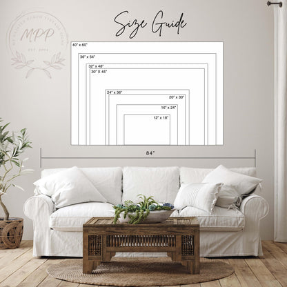 a living room with a white sofa, a wooden coffee table, and a potted plant. Above the sofa, there is a size guide with dimensions and a logo for a company.